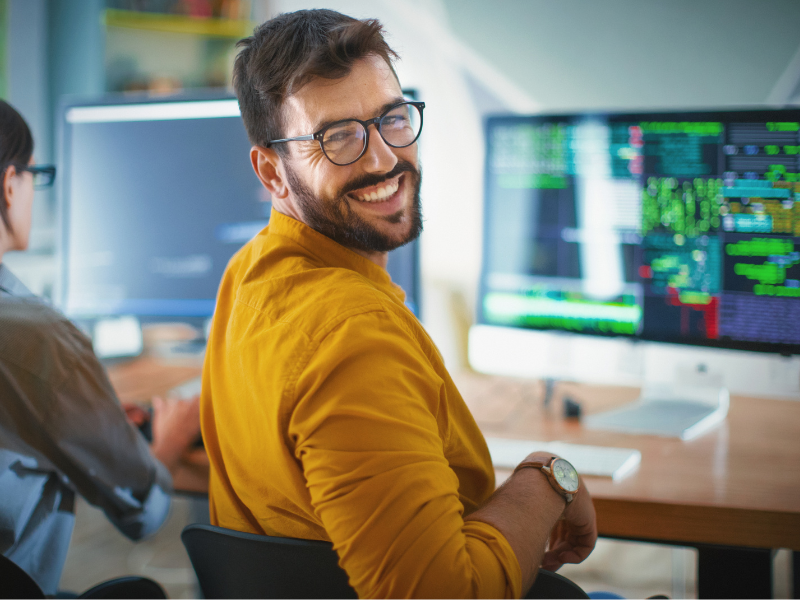 Guy happily working as an IT developer. Featured image for “Pros and Cons of Outsourcing for Small Businesses: When and How to Do It”.