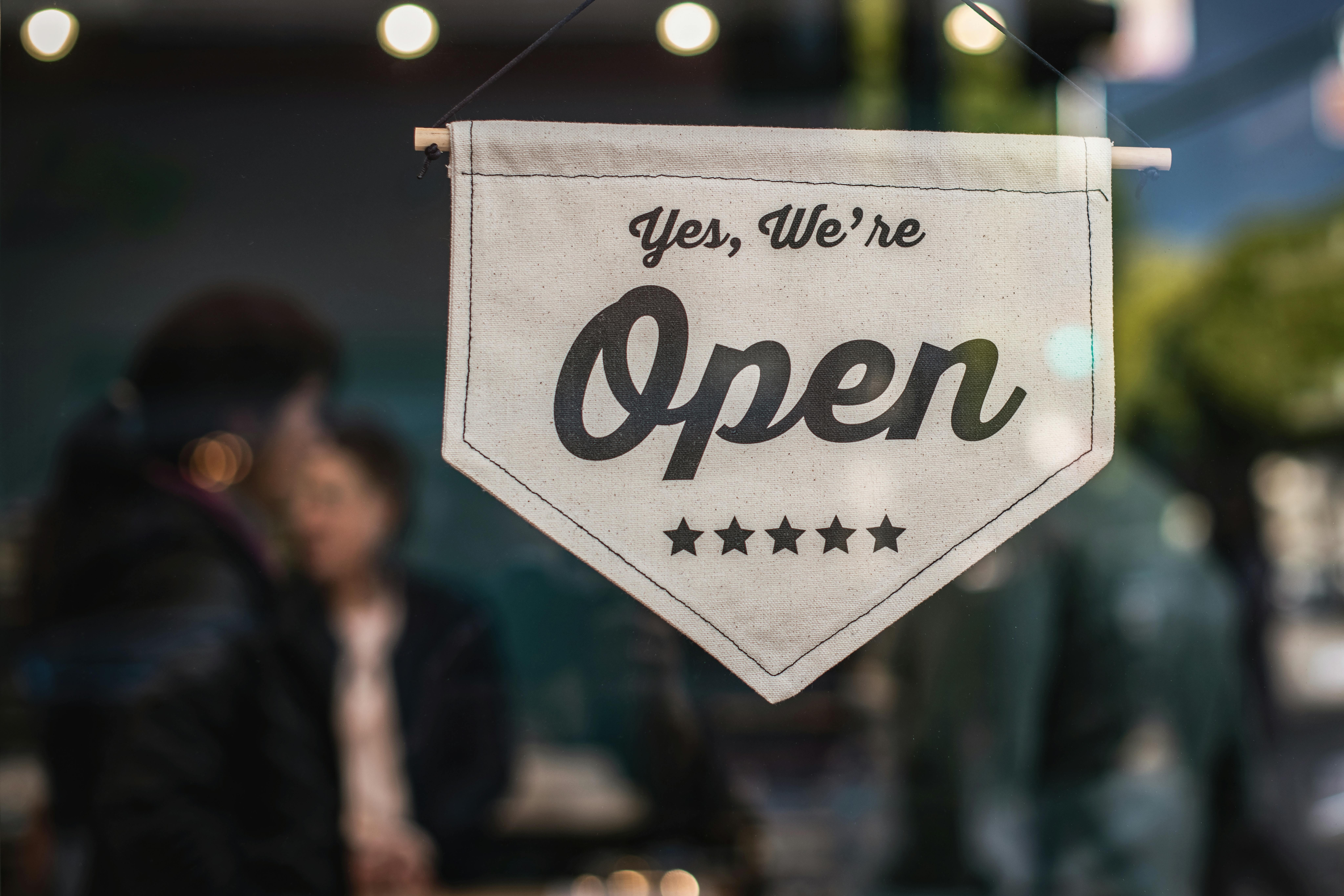 A storefront window displaying a “Yes, We’re Open” sign, symbolizing business growth made possible through top small business loans.