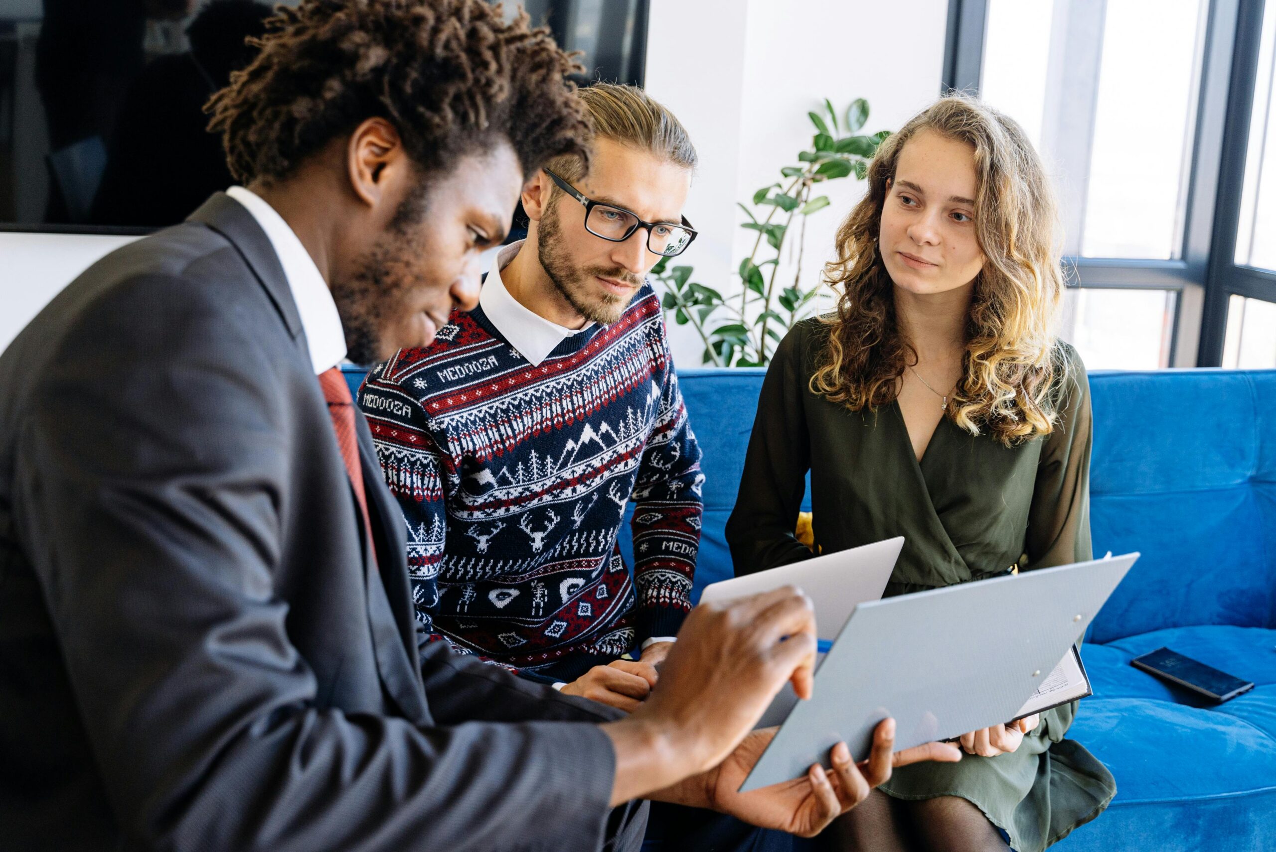 An expert using a clipboard to walk young business owners through various loan advantages and disadvantages.