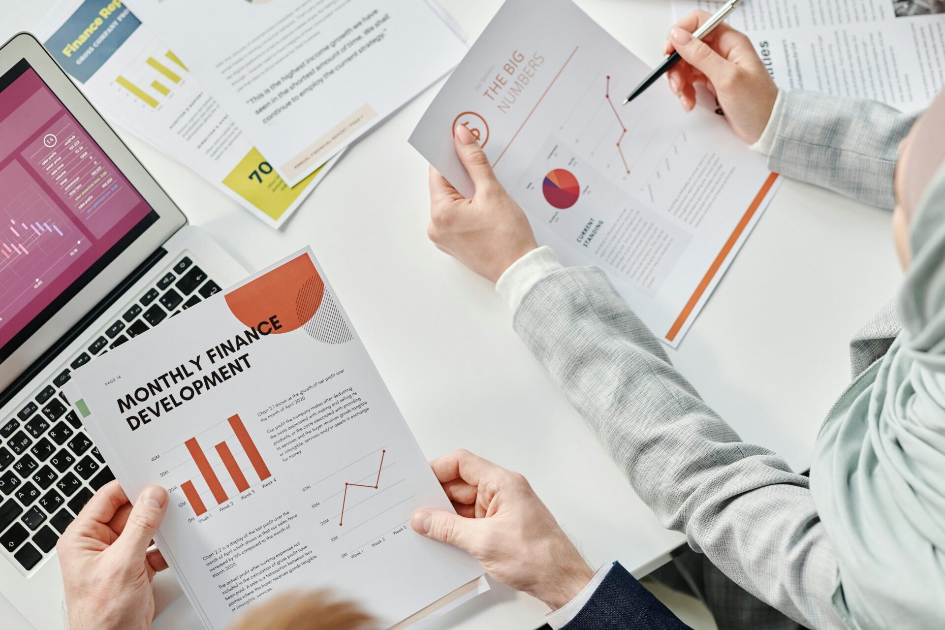 Two professionals reviewing financial charts and reports to evaluate small business funding options for growth.