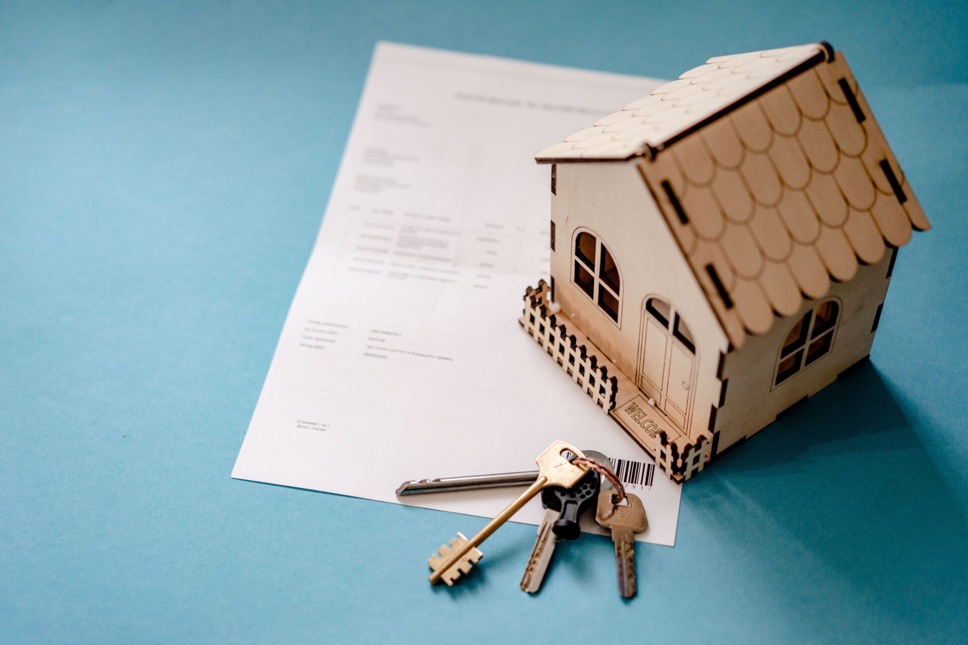 Wooden model house with keys resting on a loan document, illustrating home equity loan refinancing