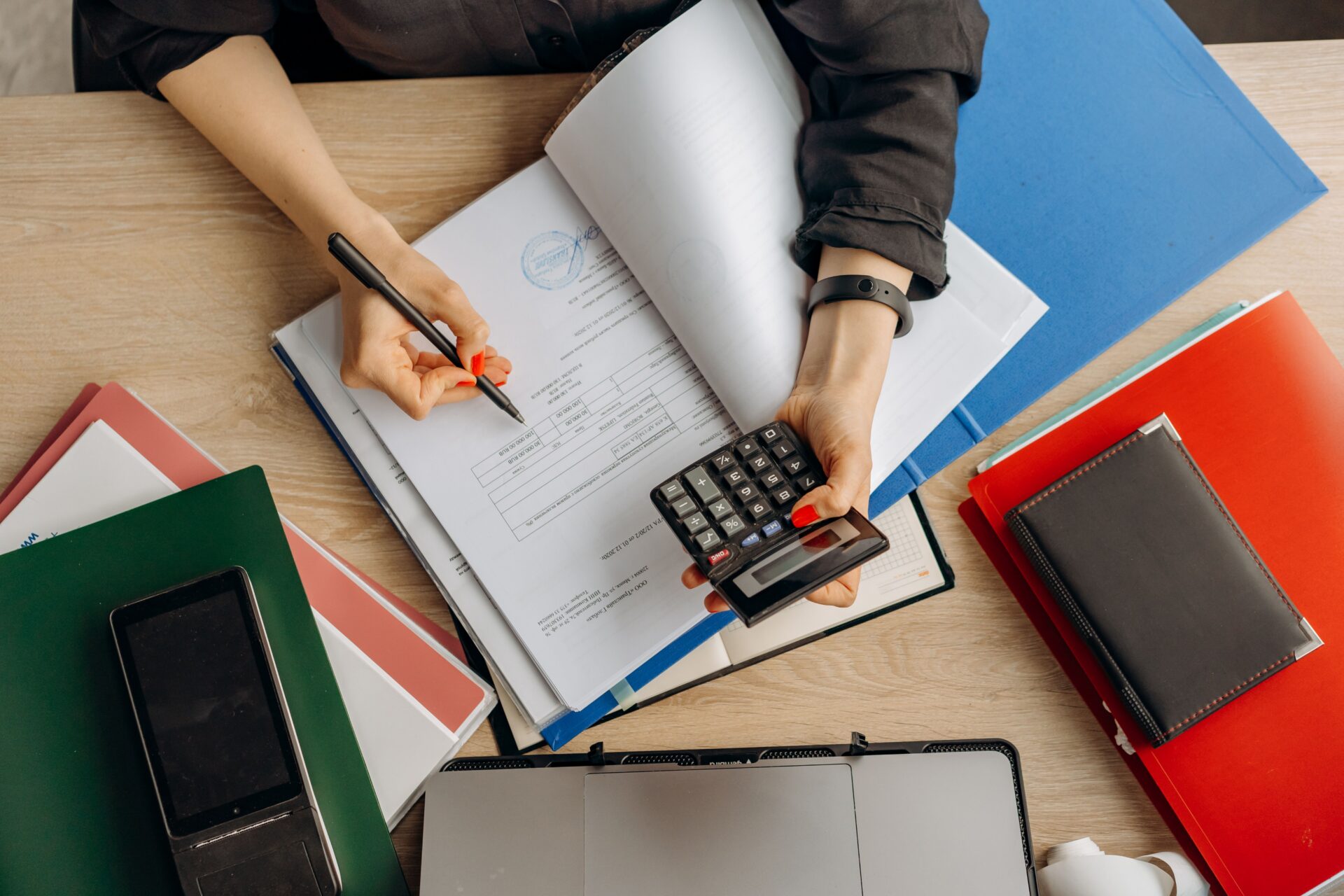 Business owner reviewing loan paperwork with a calculator while comparing SBA loan alternatives at her desk